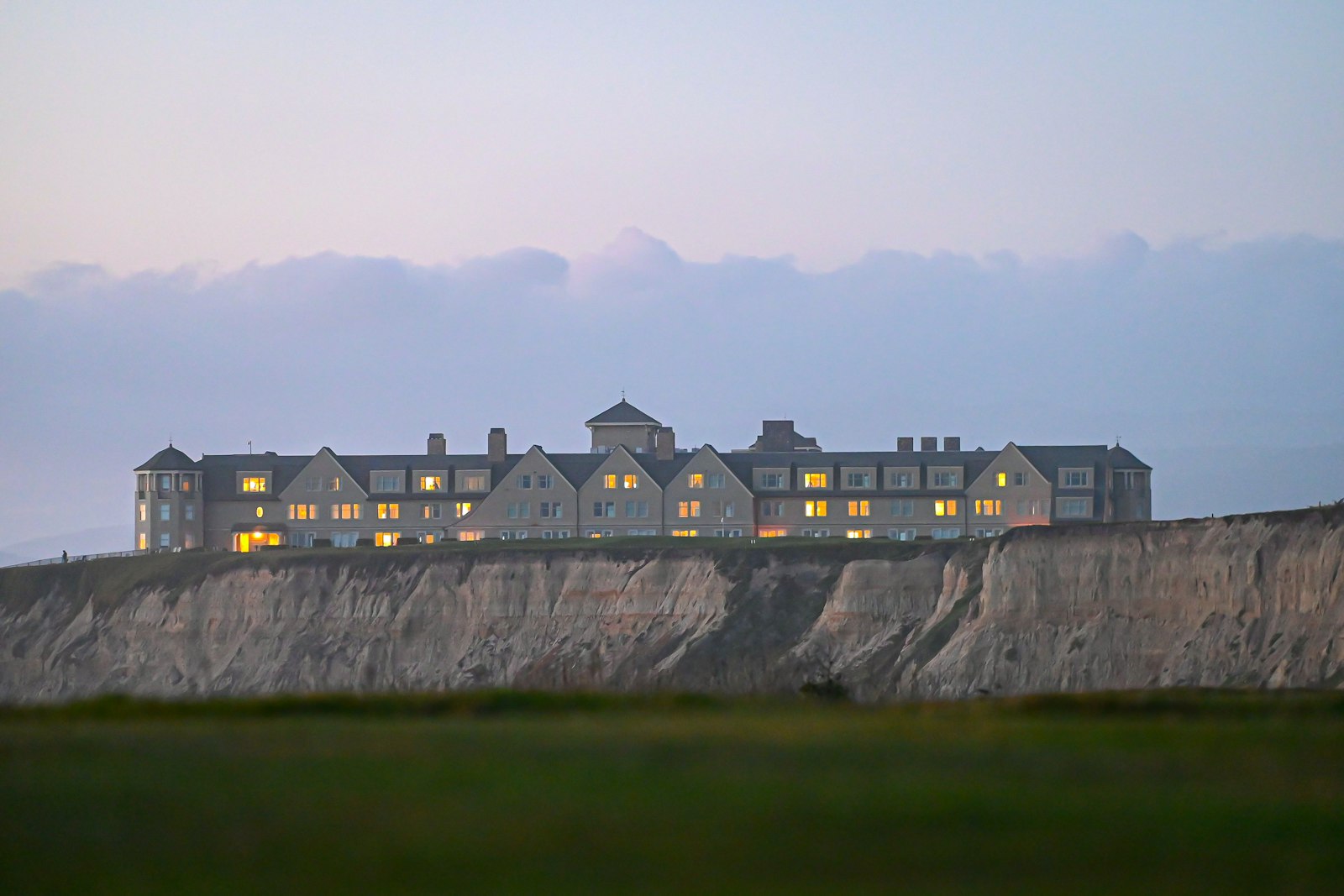 Hotel overlooking a golf links, with buildings spread along a hillside beside the course